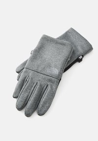 Guanti grigi realizzati in un materiale morbido, con una vestibilità aderente, quattro dita e un pollice, e il logo The North Face su ciascun guanto.