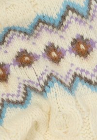 Uldstrikstof med en cremefarvet bund og zickzack-mønstre i lyseblå, lilla og brun. Blød tekstur med synlige garn detaljer.