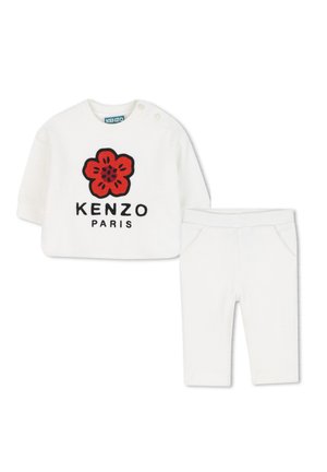 Weißes Baumwolloutfit mit einem langärmeligen Oberteil mit rotem Blumenstickerei und "KENZO PARIS"-Schriftzug, kombiniert mit passenden weißen Hosen.