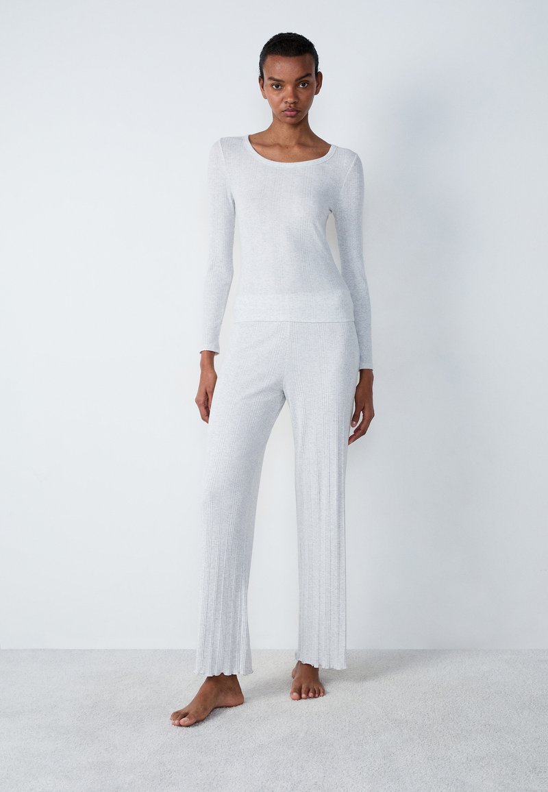 Maglietta a maniche lunghe grigio chiaro e pantaloni abbinati a coste. Design aderente con una texture liscia e orli svasati sui pantaloni.