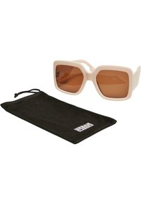 Ochelari de soare cu o ramă chunky de plastic albă off-white și lentile de culoare brown, însoțiți de un pachet moale negru cu branding alb.