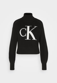 Črni skrajšani pulover z rebrasto teksturo, visokim ovratnikom in dolgimi rokavi. Na sprednji strani se ponaša z belim logotipom "CK".