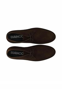 Zapatos de ante marrón con cordones, puntera redondeada, detalle de costura y una plantilla negra que presenta el logo "BIANCO".