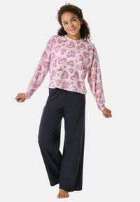 Roze lange mouw top met hartjespatronen, gecombineerd met donkere wijde broekspijpen. Zachte stof met een ontspannen pasvorm, ideaal voor loungewear.