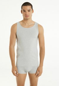 Szary bawełniany top na ramiączkach o klasycznym dekolcie w serek, zestawiony z dopasowanymi szarymi szortami. Tkanina wydaje się gładka i dopasowana.