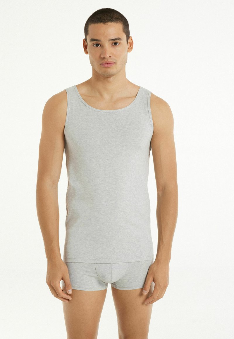 Szary bawełniany top na ramiączkach o klasycznym dekolcie w serek, zestawiony z dopasowanymi szarymi szortami. Tkanina wydaje się gładka i dopasowana.