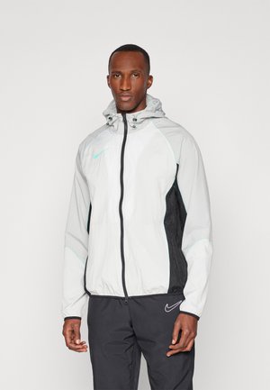 Veste légère à capuche avec un devant blanc, des côtés noirs et des accents menthe. Dispose d'une fermeture éclair sur le devant et de poignets élastiques pour un ajustement.