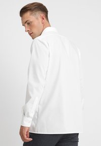 Witte langekorte mouw shirt met een klassieke kraag, knoopmanchetten, soepele katoen stof en een getailleerde pasvorm, weergegeven vanaf de achterkant.