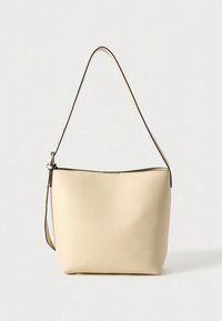 Schoudertas van crème leer met een gladde textuur, afgeronde vorm en dunne band. Voorzien van een ritssluiting en minimalistisch ontwerp.
