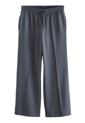 Sive široke trenirke z elastičnim pasom, vrvico za zategovanje in žepi. Izdelane iz gladkega, lahko tkanega materiala.