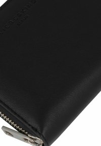 Zwarte leren portemonnee met een gestructureerd oppervlak, ritssluiting en zilverkleurige hardware. Voorzien van een ingebracht merklogo op de voorkant.