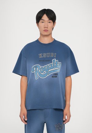 Perteklinė mėlyna medvilnė t-shirt marškiniai su "KSUBI Royalty" grafika šviesiai mėlyna ir juoda spalva, apvaliu iškirpimu ir trumpomis rankovėmis.