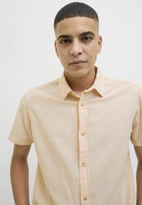 Kortek shirt met knopen in licht perzikkleurige stof met een gestructureerde afwerking en een klassieke kraag, met parelachtige knopen.
