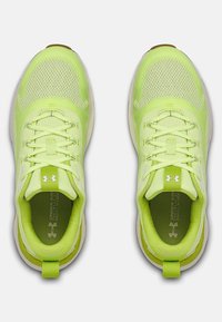 Neonowe żółte buty sportowe z siateczkowym i tekstylnym wierzchem, płaskimi sznurowadłami, amortyzowanymi podeszwami oraz logo na języku i bokach.