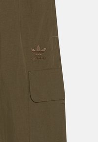 Shorts cargo vert olive avec une poche avant, arborant un logo adidas brodé en marron, fabriqués en tissu léger avec une finition texturée.