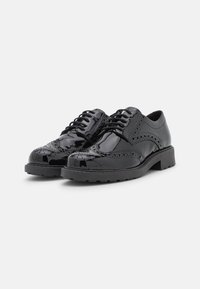 Schwarze lackierte Schuhe mit Brogue-Details, Schnürdesign und dicker Gummisohle. Sie haben eine glänzende Oberfläche und dekorative Perforationen.