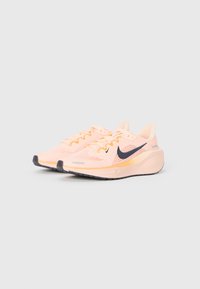 Baskets de course rose clair avec une tige en mesh respirant et un swoosh Nike bleu foncé. Dotées d'une semelle en caoutchouc texturé et d'un col rembourré pour plus de confort.