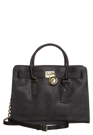 Czarna skórzana torebka Michael Kors z podwójnymi uchwytami, złotym logo w formie zawieszki oraz regulowanym paskiem na ramię z detalem złotego łańcuszka.