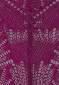 Tessuto in pizzo fucsia con intricati motivi geometrici, caratterizzato da sezioni a trama aperta e bordi ondulati, texture morbida.