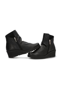 Botas de cuero negro hasta el tobillo con tacones en cuña y cremalleras laterales, con parte superior texturizada y suela de goma estriada para mayor agarre.