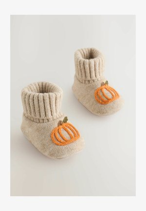 Gestrickte beige Stiefel mit gerippten Bündchen, versehen mit einer orangen Kürbisstickerei und grünen Blättern an den Seiten. Weicher, strukturierter Stoff.