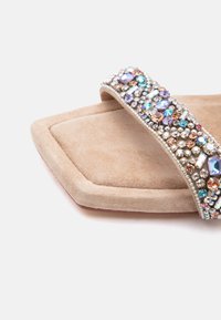 Μπεζ σουέτ σανδάλι slide με εξαγωνική μύτη και φαρδιά ταινία διακοσμημένη με πολύχρωμα στρας και χάντρες.