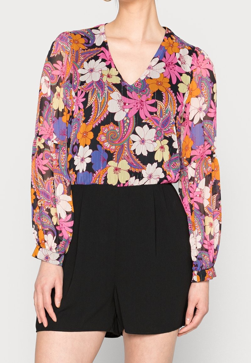 Blouse à motif floral avec un décolleté en V, ornée de fleurs colorées et de motifs cachemire sur fond noir ; assortie à un short noir.