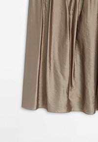 Jupe en satin beige brillante avec de doux plis et un ourlet légèrement évasé sur un fond blanc.