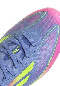 Purple athletic shoe with pink accents, textured surface, and green highlights. Features a mesh upper and a laced design for support.