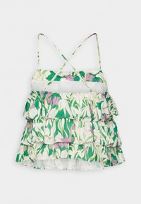 Robe sans manches à volants avec motif floral vert, blanc et violet et fines bretelles croisées sur fond blanc.