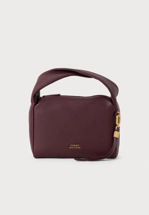 Ciemnofioletowa skórzana torebka z krótkim uchwytem, złotym zamkiem błyskawicznym i małym złotym detalem zamka, z logo Tommy Hilfiger z przodu.