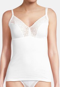 Witte cami met een V-halslijn, voorzien van florale kantdetails en verstelbare bandjes. Gemaakt van zacht katoen, met een aansluitend ontwerp en naadloze afwerking.