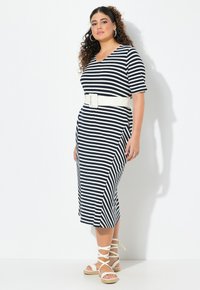 Sukienka w paski w kolorze granatowym i białym z dekoltem w serek, krótkimi rękawami i białym paskiem. Charakteryzuje się długością midi i lekkim rozkloszowaniem u dołu.