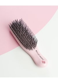 Pink hairbrush with a wide black bristle head and a smooth handle featuring a hole for hanging. Logo printed on the side.