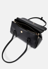 Černá kožená kabelka se zlatými doplňky, dvěma dlouhými uchy, hlavním zipovým oddělením a hladkým povrchem. Otevřená, aby byla vidět vnitřní část.