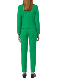 Grüner, maßgeschneiderter Anzug mit einem taillierten Blazer und schmalen Hosen. Der Stoff wirkt glatt, mit minimalen Nähten und einem strukturierten Design.