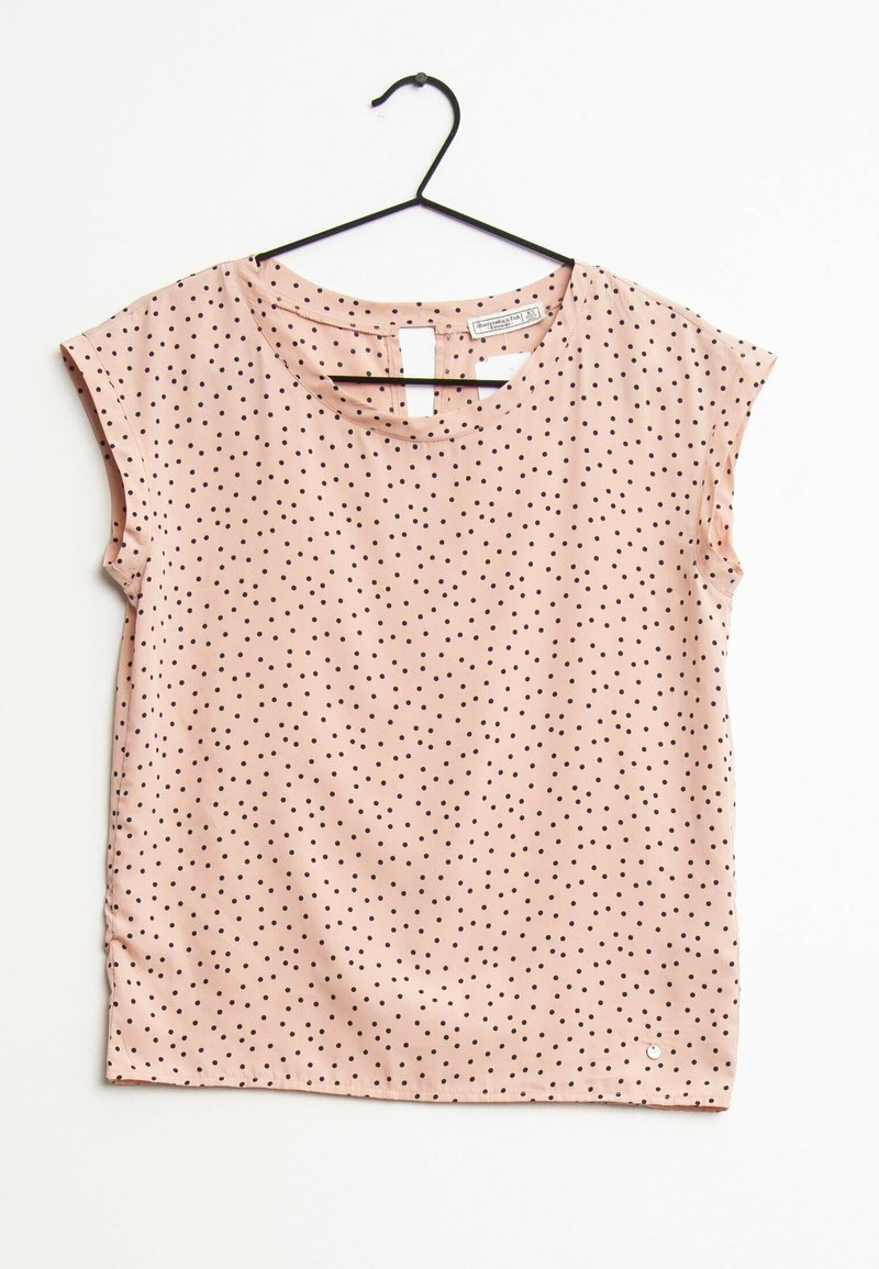 Różowa bluzka z krótkim rękawem w czarne kropki, okrągły dekolt i małe wycięcie z tyłu. Gładki materiał o lekko błyszczącej powierzchni.