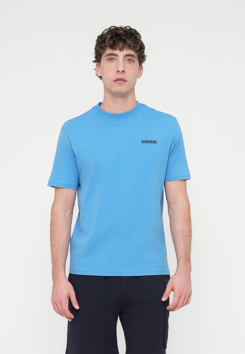 Μπλε κοντομάνικο μπλουζάκι με στρογγυλή λαιμόκοψη και μαύρη λεπτομέρεια λογότυπου στο πάνω αριστερό μέρος, κατασκευασμένο από απαλό, ελαφρύ ύφασμα.