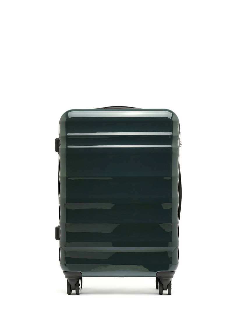 Valigia rigida di colore verde scuro, con una finitura lucida, righe verticali e quattro ruote per la mobilità. Maniglie laterali per un facile sollevamento.