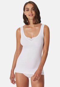 White cotton tank top with a scoop neckline, featuring lace trim with a heart pattern. Smooth texture, fitted design, and no sleeves.