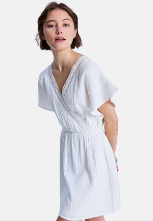 Rochie albă cu mâneci scurte evazate și decolteu în V, având detalii din dantelă de-a lungul decolteului și talie adunată pentru o croială lejeră.