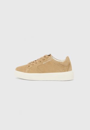 Tan suede sneaker with white rubber sole. Rounded toe, classic lace-up design, and brand name displayed in white on the side.
