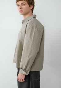 Karierte Button-Up-Shirt in erdigen Tönen, mit Kentkragen, langen Ärmeln, einer Brusttasche und entspannter Passform.