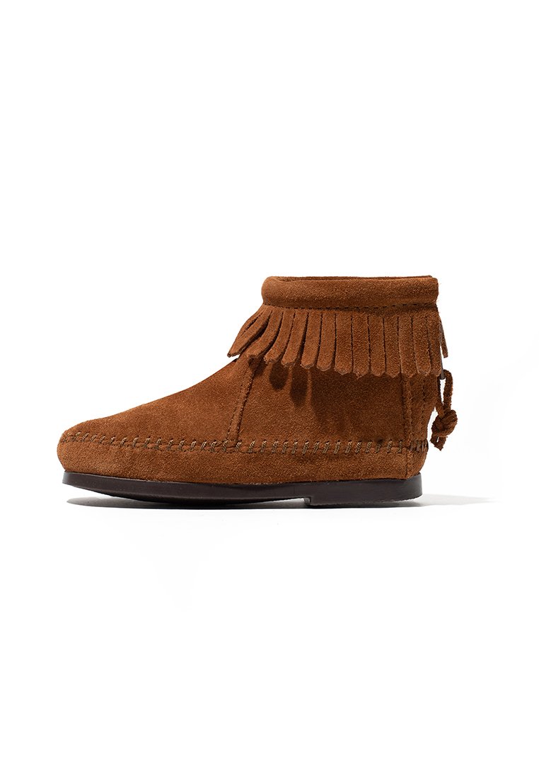 Bota de ante marrón hasta el tobillo con puño flecado, punta redondeada y costuras decorativas a lo largo del costado. Suela de goma plana en la base.