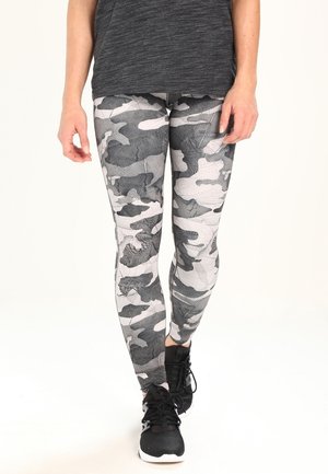 Leggings en camouflage noir et gris avec un design ajusté et un tissu extensible. Associés à des chaussures de sport noires et un haut gris foncé.