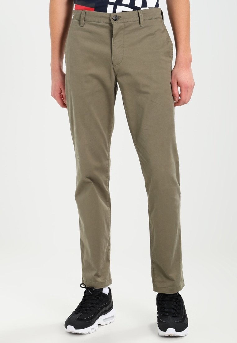 Chinos color khaki in cotone, con una vestibilità dritta, una superficie liscia, tasche frontali e chiusura a bottone. Indossati con sneakers nere.