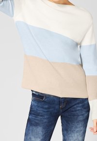 Lätt tröja med horisontella ränder i vitt, ljusblått och beige. Mjuk stickad textur, vid halsringning, avslappnad passform.