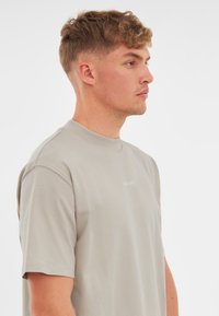 Világosszürke pamut póló kerek nyakkal és rövid ujjakkal. Finoman nyomtatott márkajelzéssel az elején. Simaság jellemzi, laza fazonú.