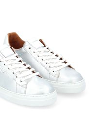 Sneaker metallici argento con lacci bianchi, tomaia in pelle testurizzata e suola in gomma. L'interno presenta dettagli marroni. Design semplice e a basso profilo.