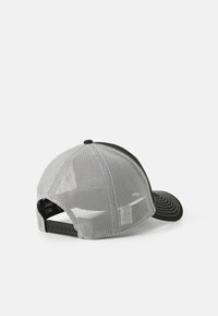 Gorra negra y gris con una parte trasera de malla texturizada, visera curvada y correa de plástico ajustable, con costuras blancas a lo largo de la visera.